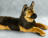 Life-sized weighted German shepherd plush in a lay-down pose on gray backdrop—realistic coat and face.