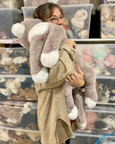 Adult holding a large weighted gray and white cat plush to show size and drapey body
