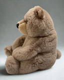 Side profile of grayish-brown weighted bear seated, showing large belly and soft fur texture.