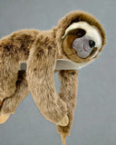 Brown and tan weighted sloth plush in a hanging view with arms and legs dangling on gray backgraound.  Friendly face, soft fur, cozy calming plush.