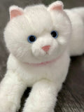 Close-up of fluffy white weighted cat plush with pink nose and blue eyes.