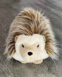 Weighted hedgehog plush with long soft ‘quills’ facing forward on gray background.