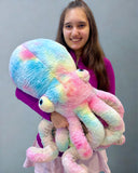 Model hugging a soft Tie-dye pink-blue-yellow weighted octopus plush showing bouncy textured tentacles and large size.