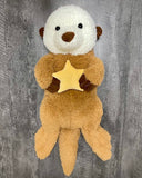 36-inch weighted sea otter plush holding a yellow star, full-body view on gray wood background
