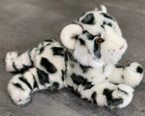 Three-quarter angle of snow leopard cub in a laying pose; ultra-soft rosetted coat and floppy paws; gentle weighted comfort.