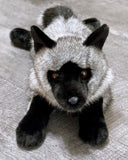 Weighted gray fox plush in a laying pose on gray floor—front close-up of face and ears.
