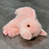 Pink pig plush on its side with head tilted; floppy legs and soft snout; weighted for soothing cuddles.