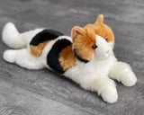Weighted Calico cat stretched out on gray surface—soft faux-fur lap companion, up to 4 lbs.