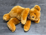 Oversized ultra-plush weighted teddy bear lying on its side, showing soft, fluffy fur and huggable body.