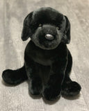 Front view of 23-inch weighted Black Labrador retriever plush sitting; plush black coat, floppy paws, lifelike nose and eyes.