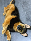 Lifelike oversized 40" weighted German Shepherd plush lying on its back with floppy legs; tan-and-black faux fur on gray floor.