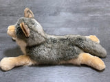 Realistic weighted wolf stuffed animal in low-profile pose, soft grey coat and fluffy tail.