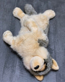 Weighted wolf plush on its back revealing soft cream belly and cuddly construction.