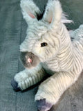 Close side view of zebra plush head and forepaws; ultra-soft gray stripes, pink nose; weighted for soothing hugs.