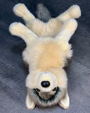 Top view of 18-inch weighted gray wolf plush lying on its back with floppy legs and fluffy tail.