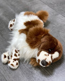 Floppy-eared weighted spaniel plush resting head on paws, brown-and-white coat,
