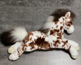 Overhead side view of weighted appaloosa horse plush showing spotted brown and white coat and realistic body shape in a floppy pose.