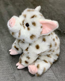 Sitting view of weighted spotted pig plush with perky ears and rosy nose; chubby-bodied cozy sensory companion.