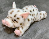 Three-quarter angle of spotted pig plush in a laying pose; pink ears and snout; up to 5 lbs.