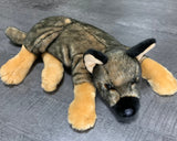 15-inch weighted German Shepherd plush lying on its side, black-and-tan coat with large tan paws and black muzzle on gray floor.