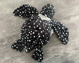 Overhead view of 15-inch weighted black with white spots sea turtle plush with realistic raised shell ridges and wide spotted flippers.