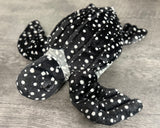 Angled view of black with white spots sea turtle weighted stuffed animal showing white spotted shell, lifelike face, and broad front flippers.