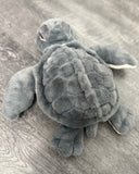 Overhead view of gray weighted sea turtle plush showing the detailed textured shell and floppy flippers.