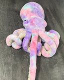 Back view of weighted plush octopus in purple pink blue gradient showing long plush elastic tentacles outstretched. 