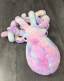 Front angle of purple pink blue weighted octopus with blue eyes and curled tentacles