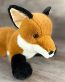 Close-up of weighted fox plush face with amber eyes, black ears, and soft white muzzle