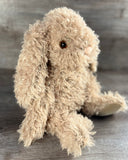 Side front view of weighted curly bunny stuffed animal with long floppy ears and curly plush fur.