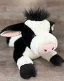 Close-up of a weighted Holstein cow plush with a soft pink nose and black-and-white fur.