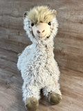 Front view of oversized weighted llama stuffed animal with a smiling face, fluffy tuft of hair, curly cream fur, and long floppy front legs.