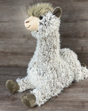 Oversized shaggy weighted llama plush sitting with its long neck upright, floppy legs extended, and soft brown hooves.