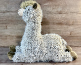 Side view of oversized shaggy weighted llama plush sitting with its long neck upright, floppy legs extended, and soft brown hooves.