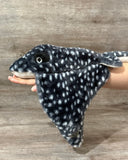 A black with white spots weighted stingray plush laying on a persons arm to show the floppy drape of the wings. Up to 6lbs for deep pressure comfort.
