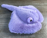 Lavender weighted stingray plush with fluffy purple fur, wide wings, expressive eyes, and soft tail, measuring 20 inches long.