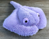 Close-up of soft lavender weighted stingray stuffed animal showing fluffy fur, rounded body, and sweet black eyes.
