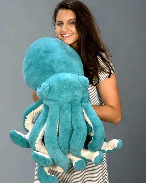 Person holding a large teal octopus plush to show size and textured tentacles
