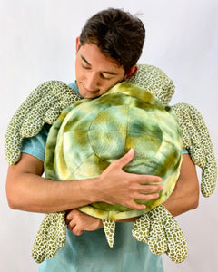A man holding a realistic sea turtle weighted up to 12-pounds stuffed animal for anxiety, ADHD, PTSD, autism, Alzheimer's.
